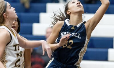 Female basketball player in blue jumps to score amid opponents.