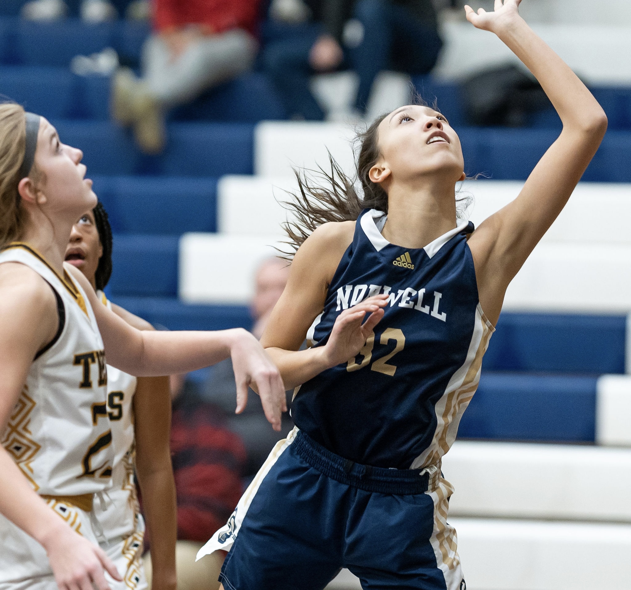 Female basketball player in blue jumps to score amid opponents.