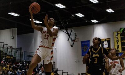 High school basketball player leaps for a layup during a game.