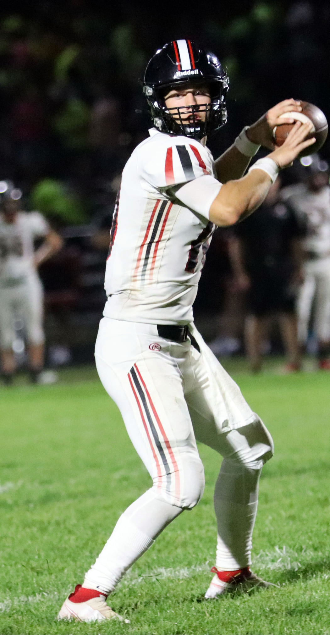 Football player preparing to throw the ball during a night game.