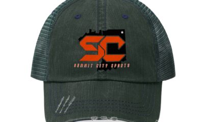 Dark green distressed baseball cap with orange SC logo and slogan.