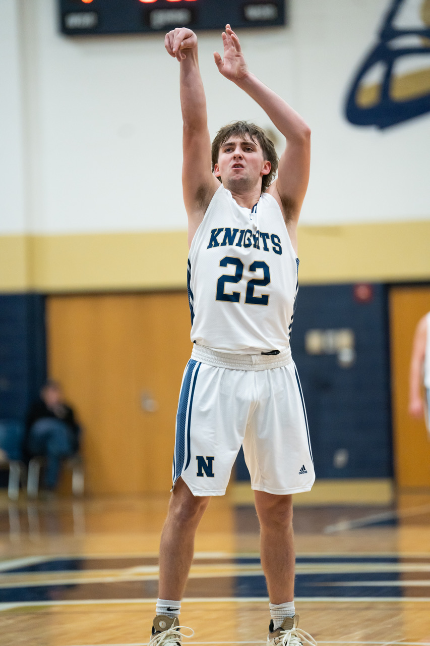 Basketball player in white Knights jersey taking a shot.