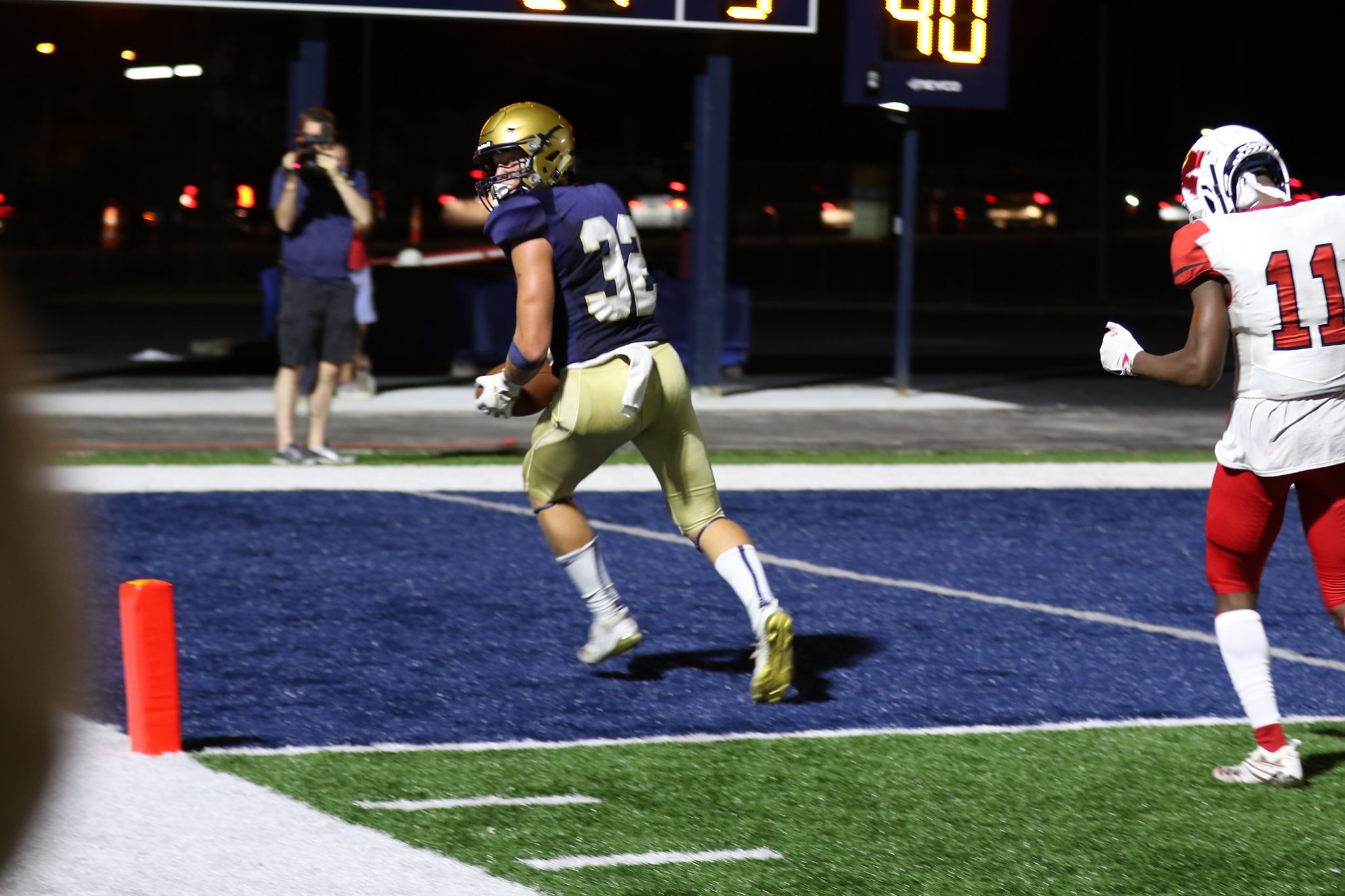 Football player running on the field during a night game.