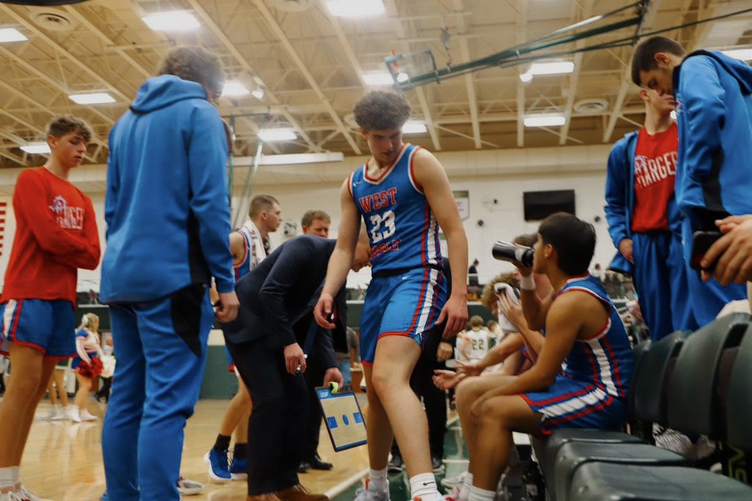 Basketball players and coach interacting during a game break in a gym.