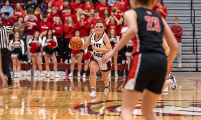 Female basketball player dribbling during a game with a crowd in the background.