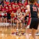 Female basketball player dribbling during a game with a crowd in the background.