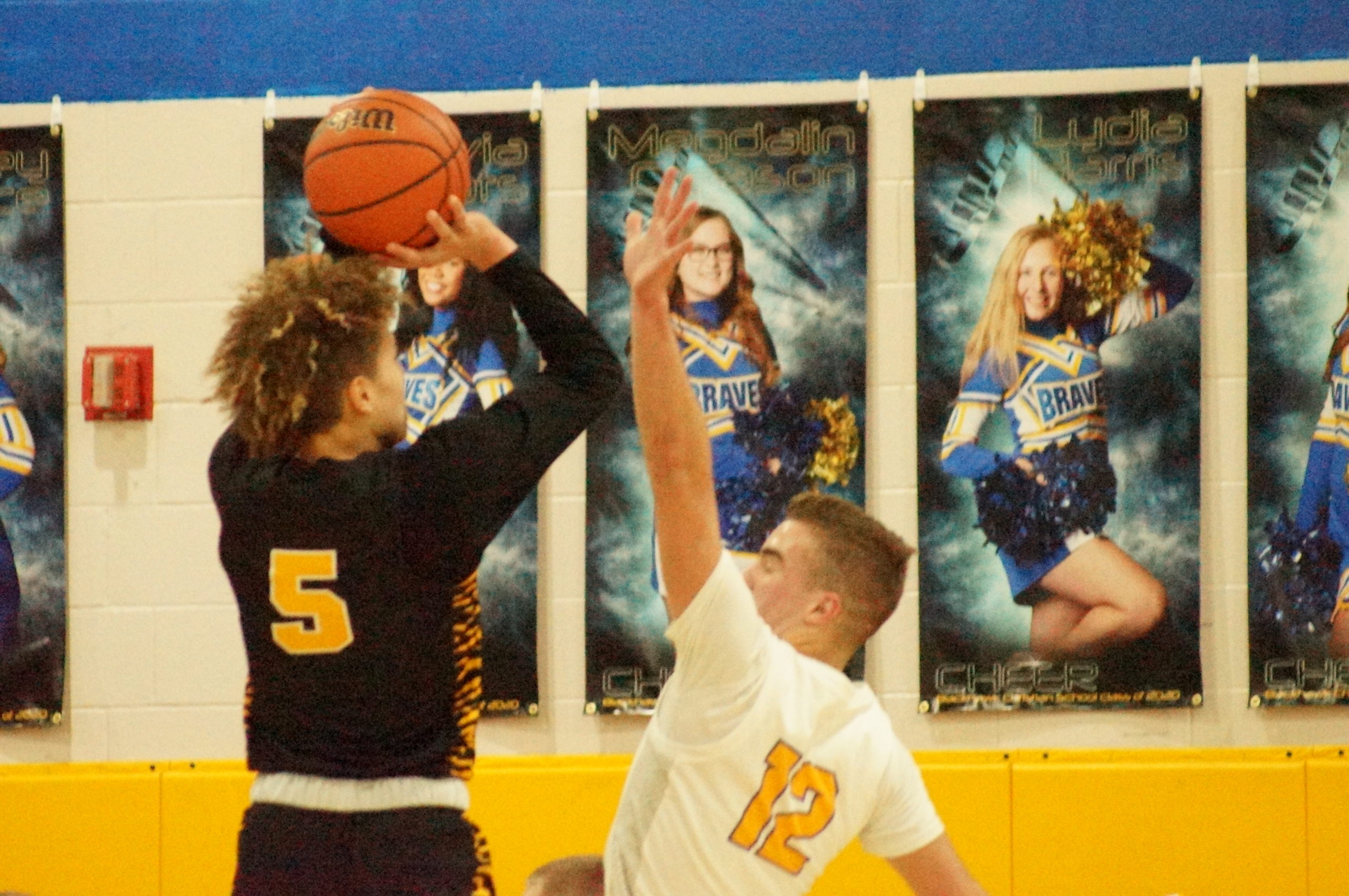 A basketball player in black shoots over a defender in white.