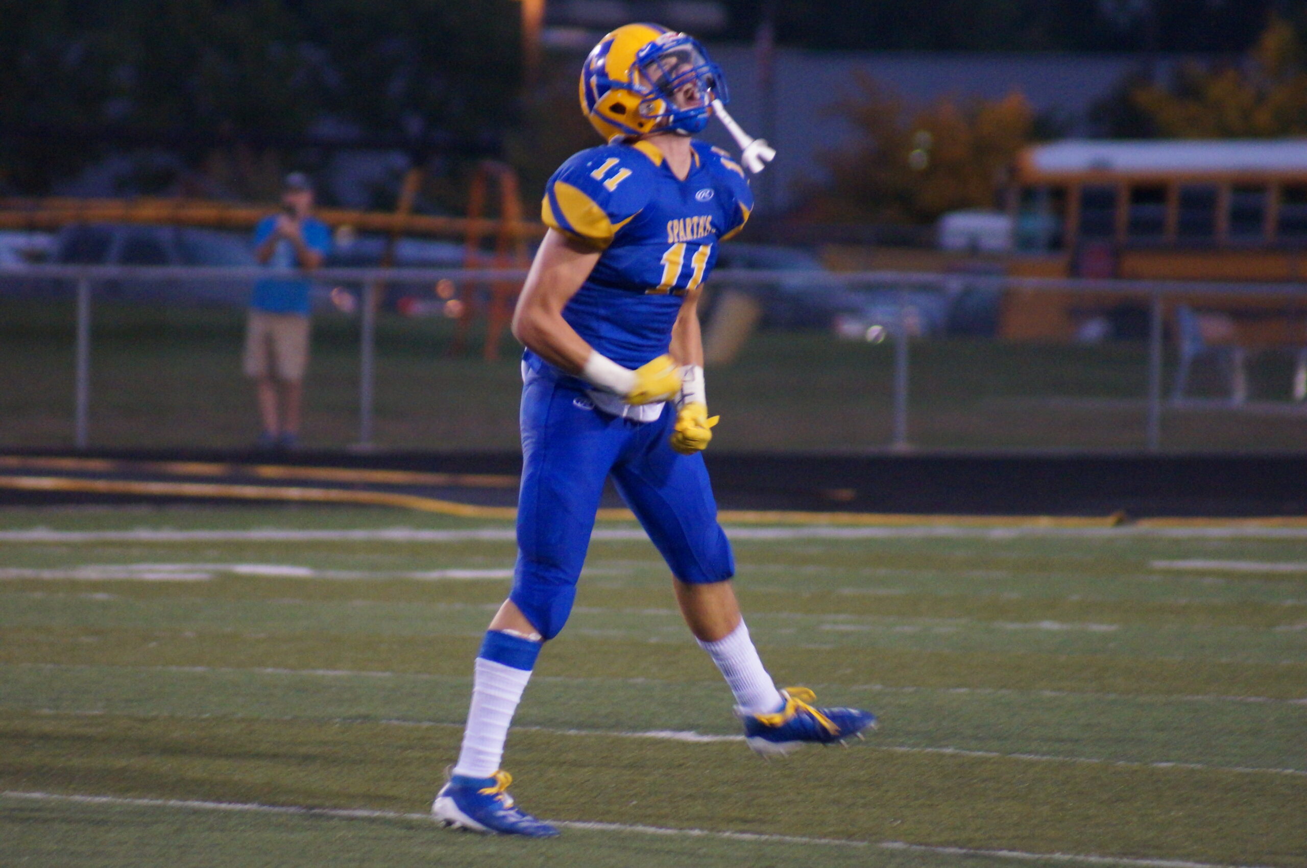 Football player in blue and yellow uniform standing on field.