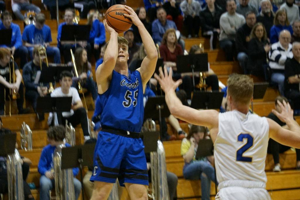 Basketball player in blue jersey shooting over defender in white jersey.