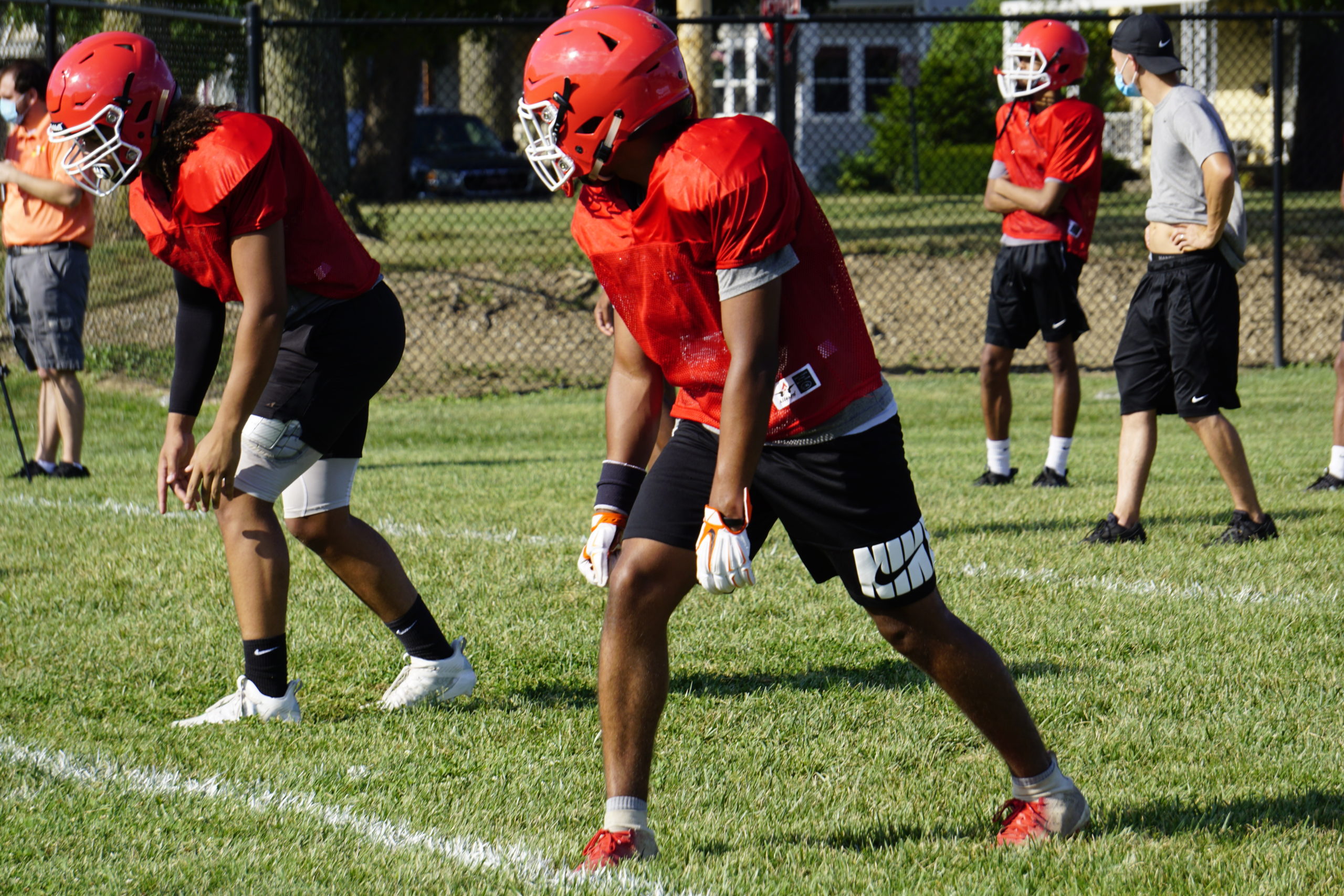 Football player in red jersey preparing to start a play on the field.