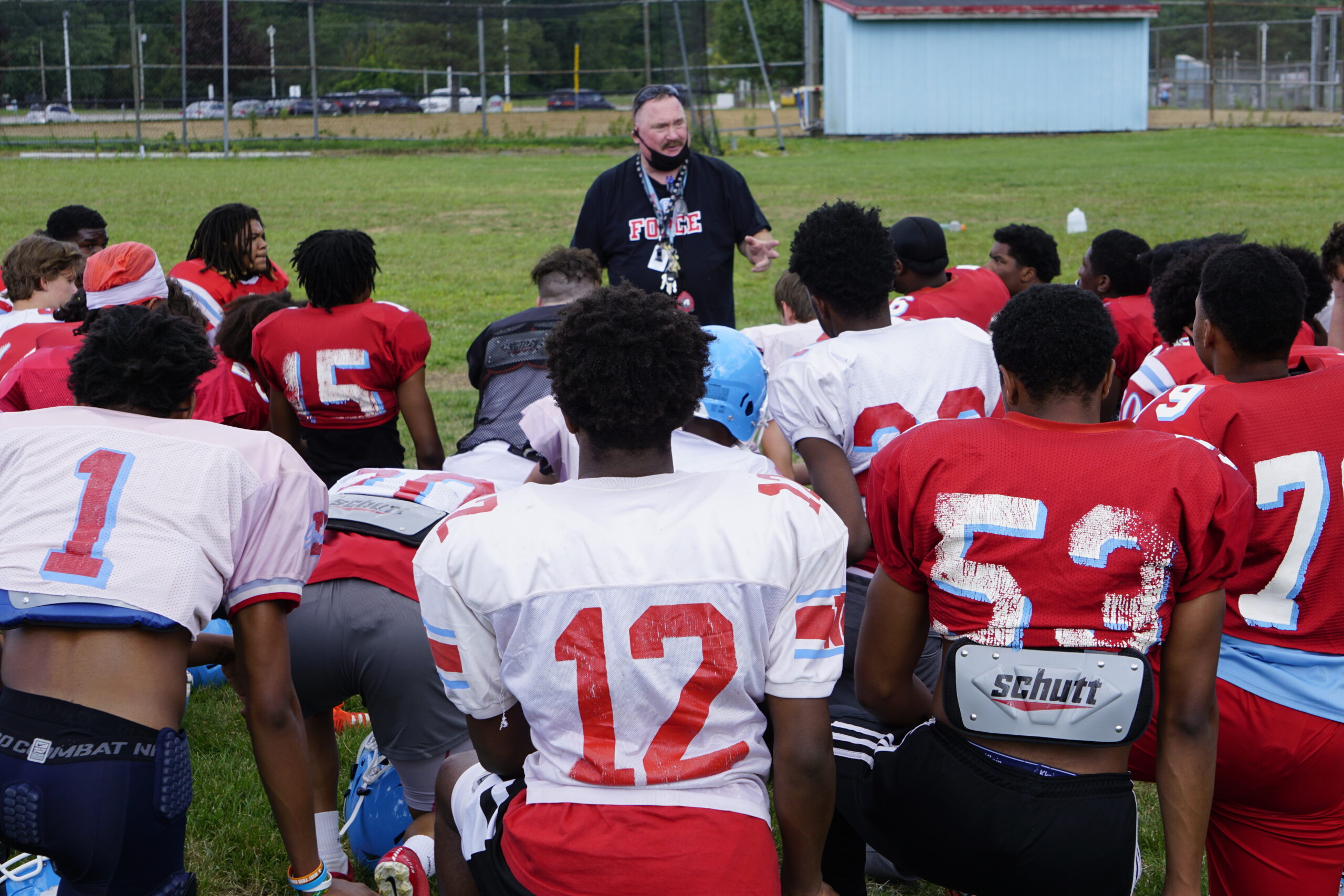 Football coach addressing his team during practice.