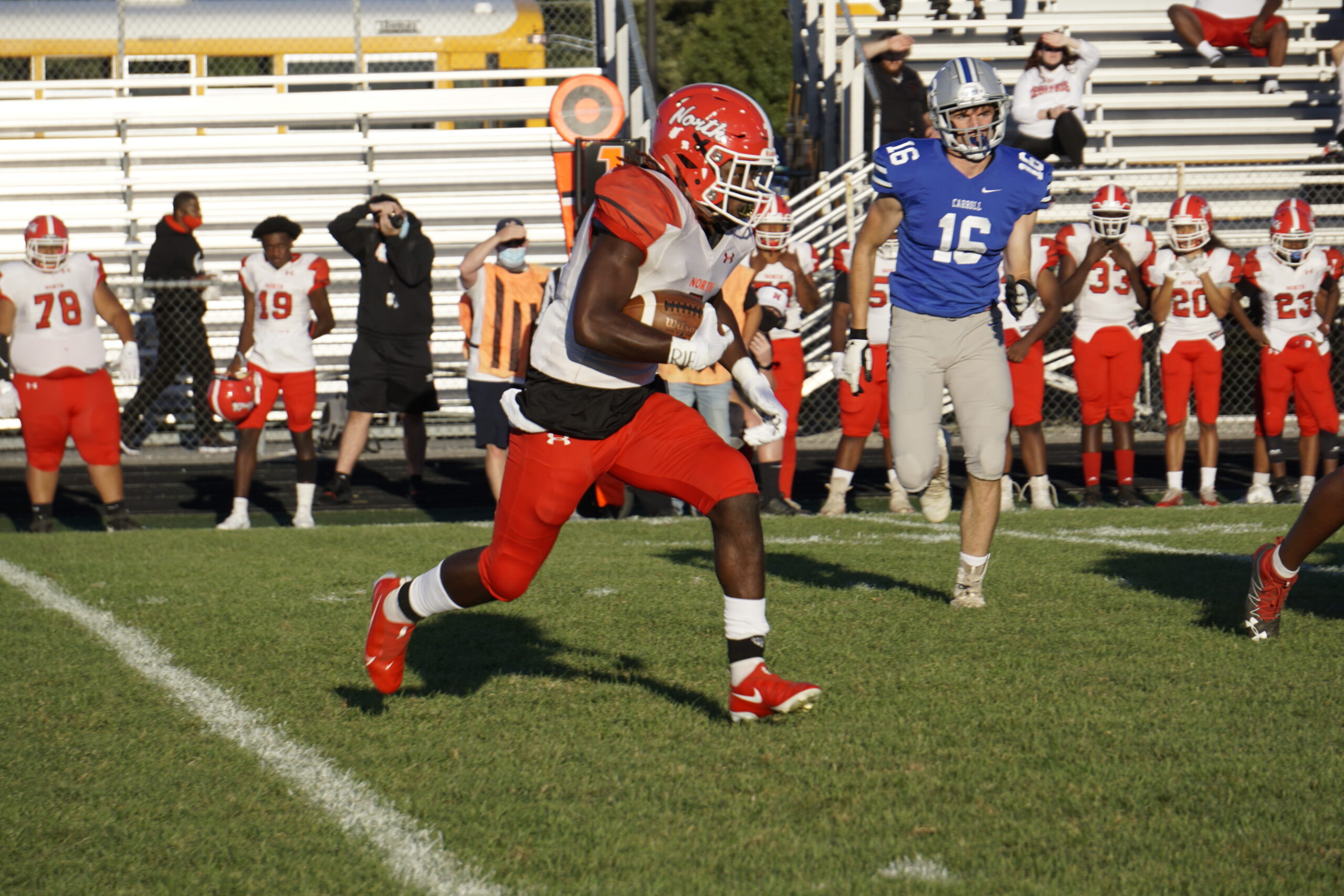 High school football player running with the ball during a game.