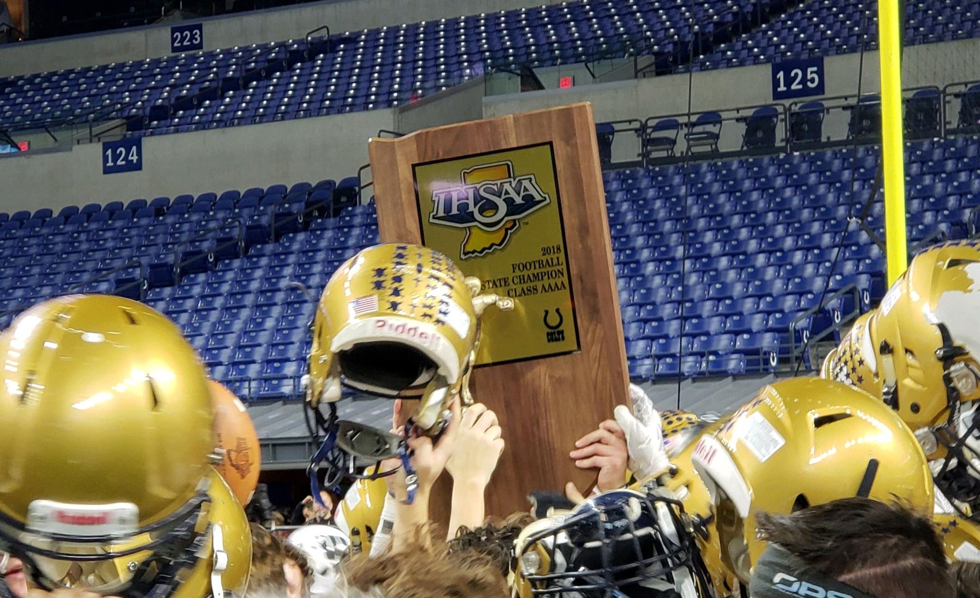Football players celebrate with a championship trophy in a stadium.
