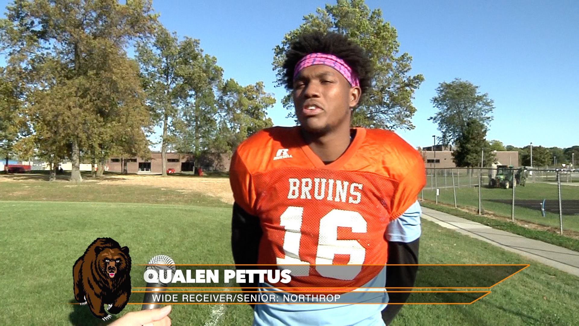 High school football player in orange jersey during practice.