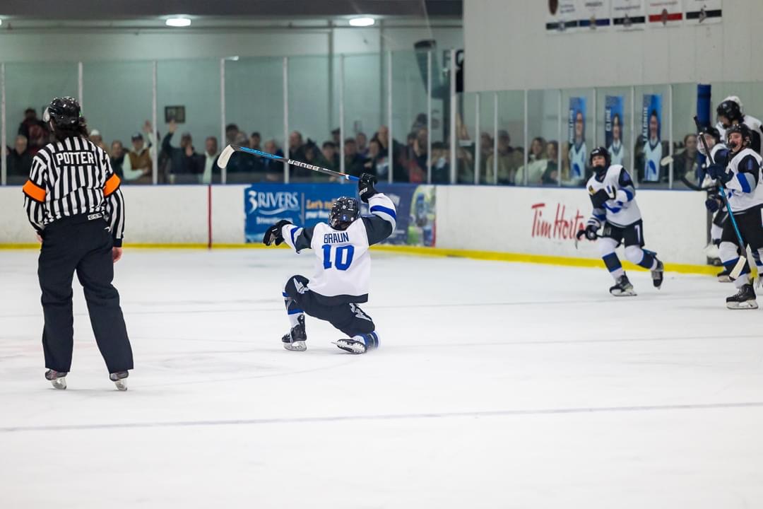 Ice hockey player celebrating on the rink after scoring a goal.