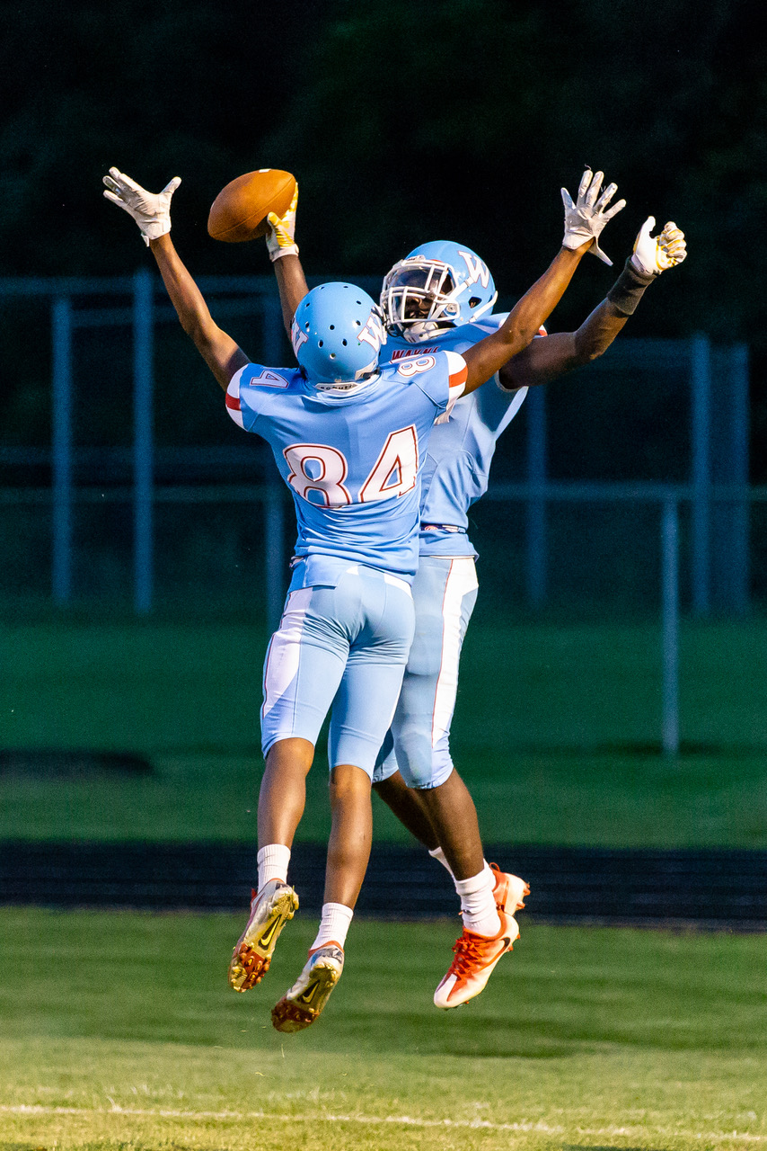 Two football players celebrating on the field at night.