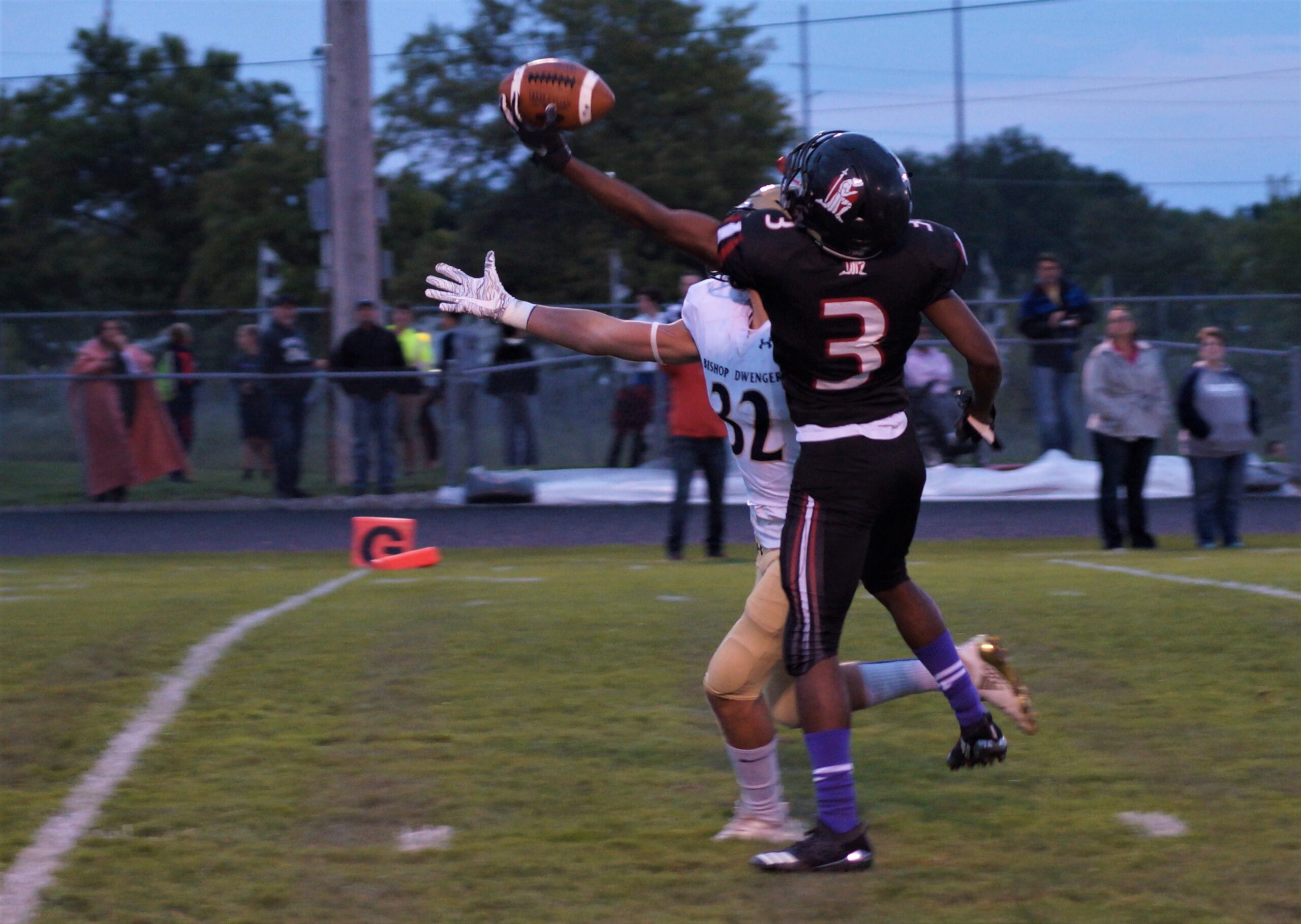 Football player catching a touchdown pass near the end zone.