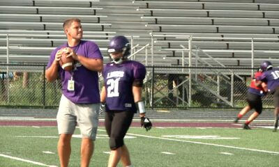 Coach instructing football player on field during practice.
