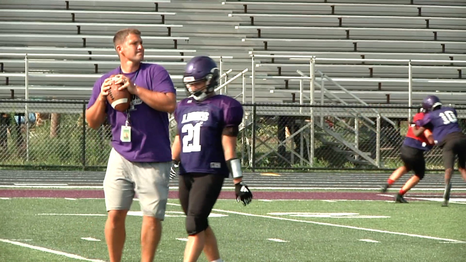 Coach instructing football player on field during practice.