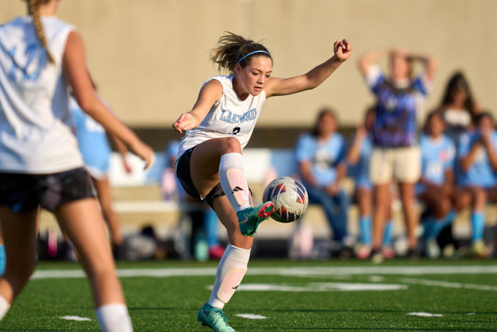 Soccer player kicking ball on field.
