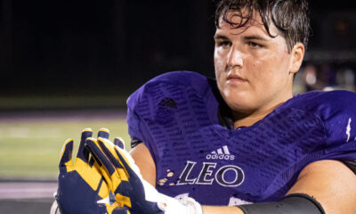 Close-up of a focused football player in purple Leo uniform and gloves.