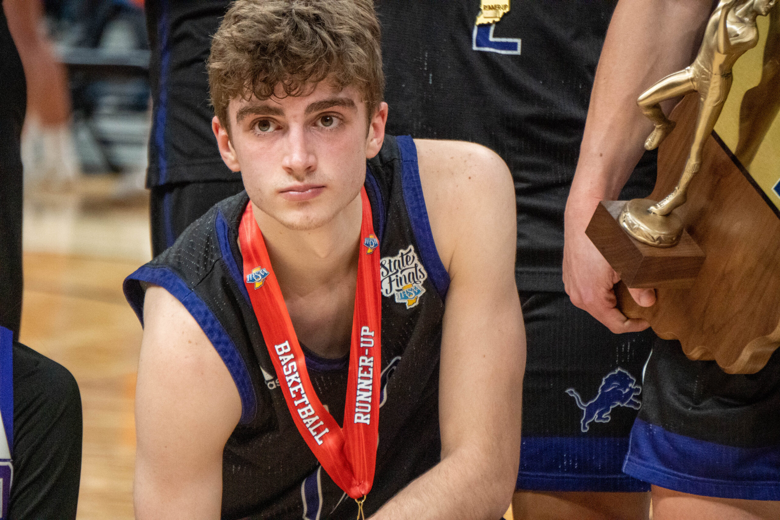 Young basketball player wearing a runner-up medal during state finals.