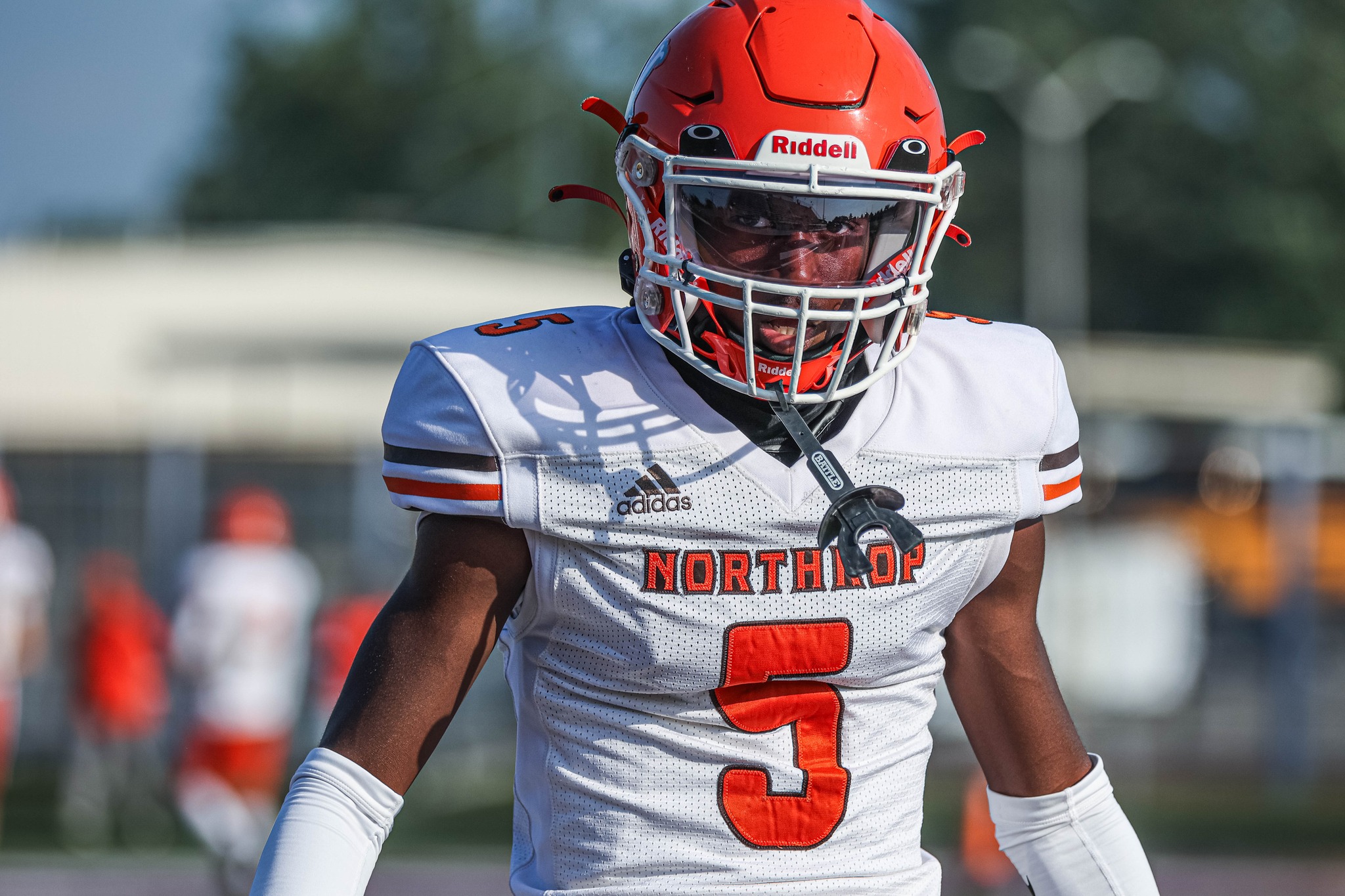 Football player wearing a red helmet and white jersey with number 3.