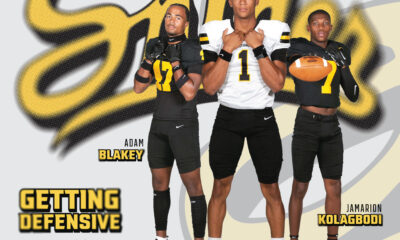 Three high school football players pose confidently in front of their team logo.