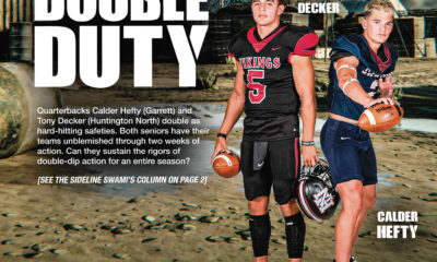 Two high school football players standing side by side on a field.