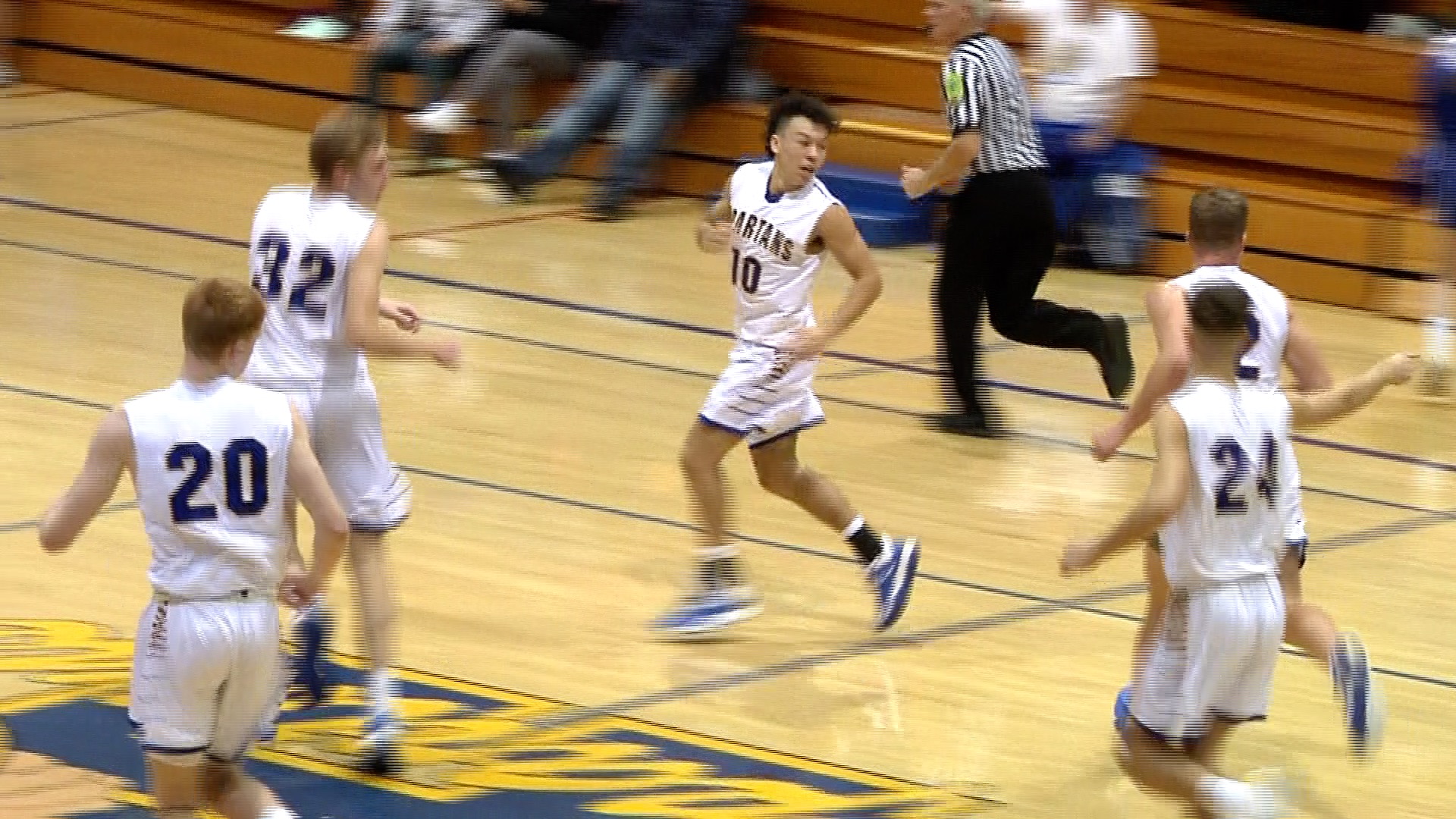 High school basketball player running during a game on a gym court.